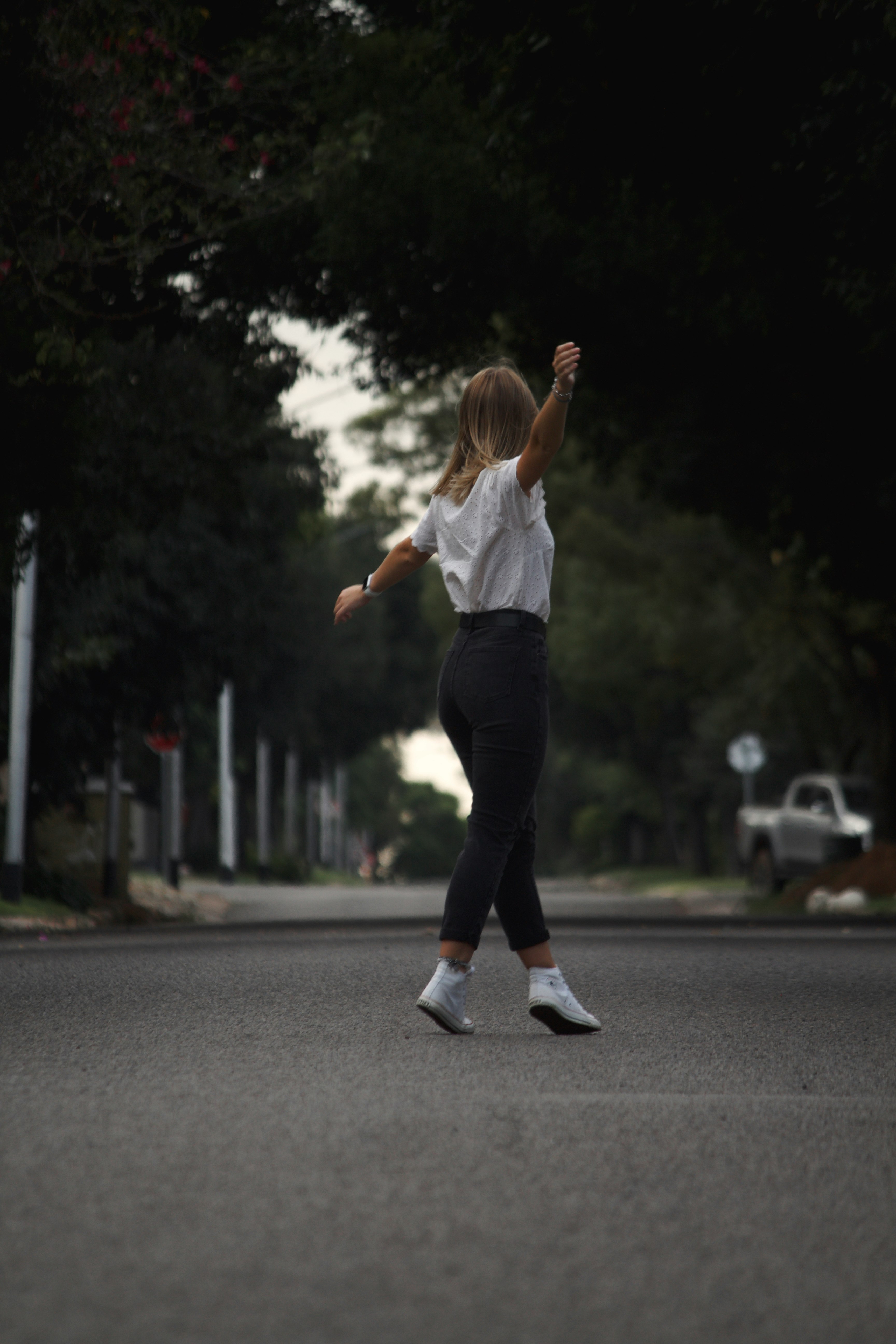 woman in white shirt and black pants running on road during daytime